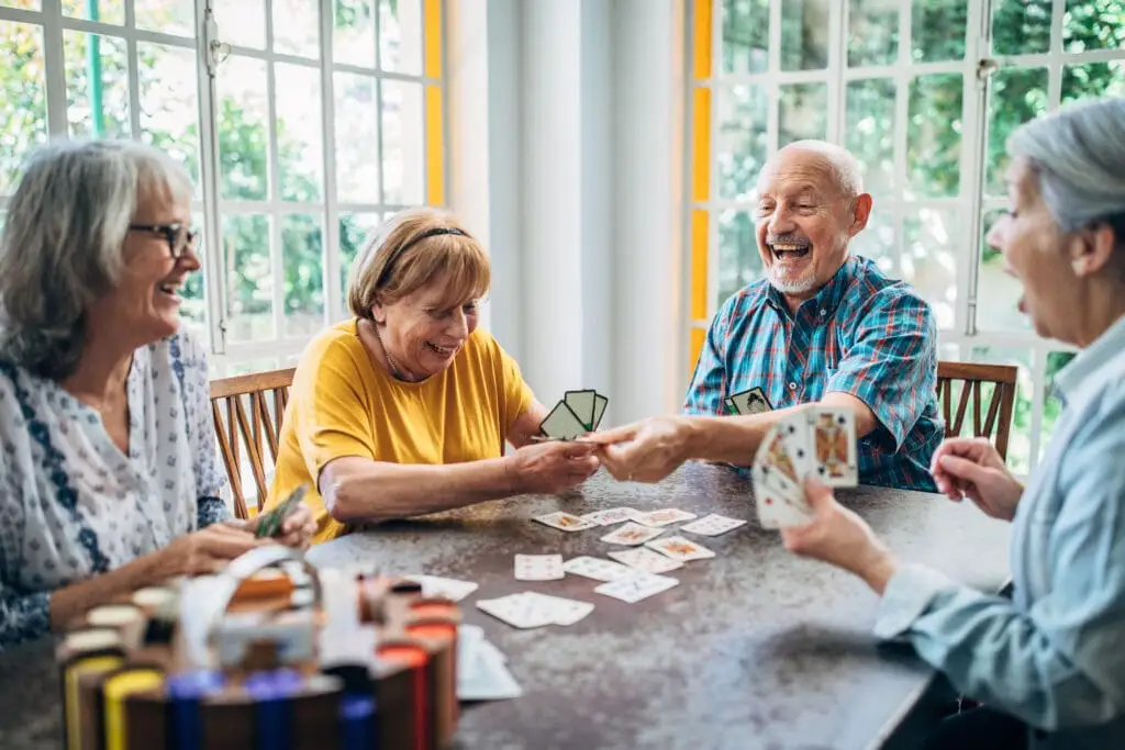 A group of elderly adults in a card playing club for seniors at Charter Senior Living of Bay City in Michigan